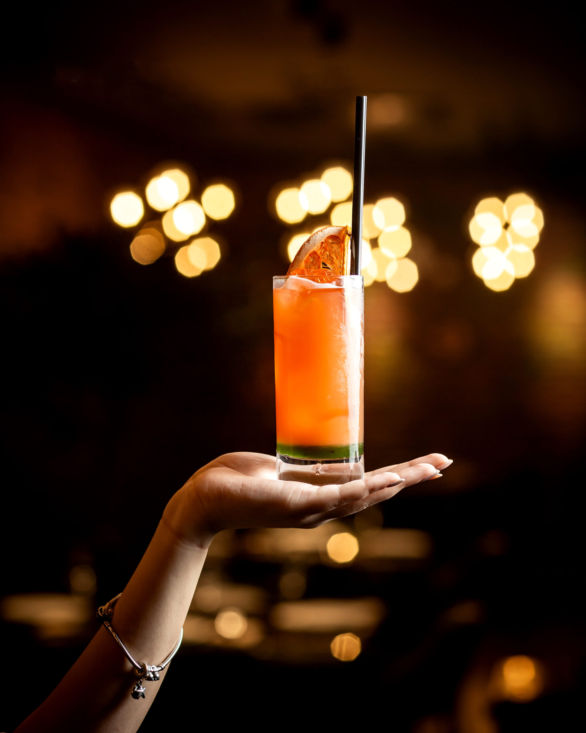 woman hand holding grapefruit cocktail with black straw